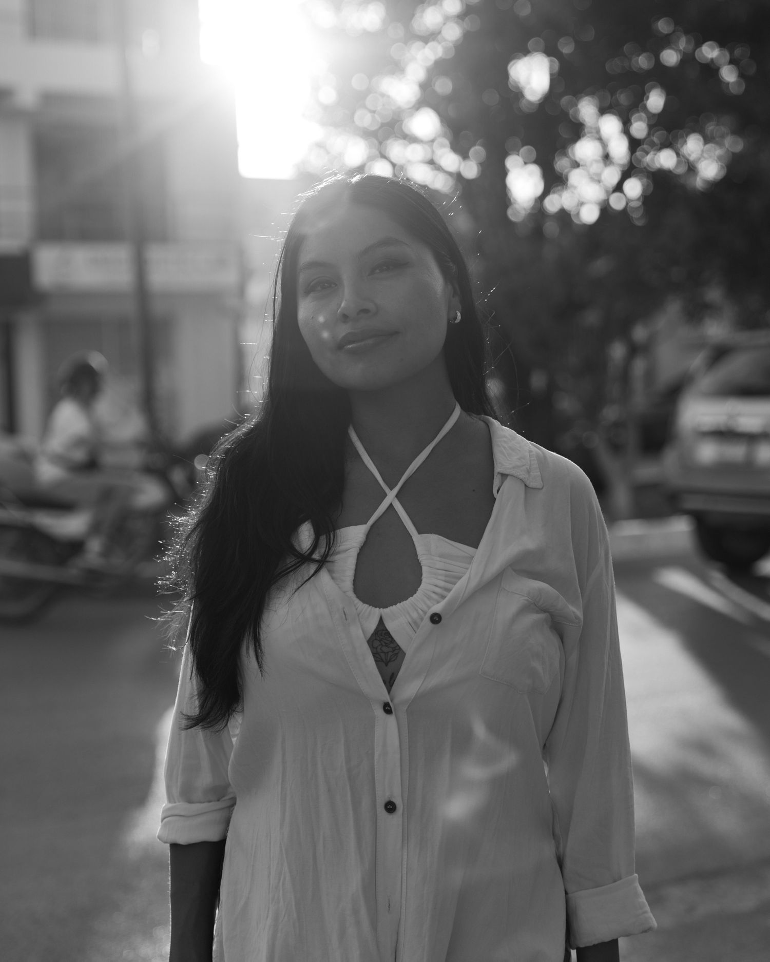 Woman on a sunlit street in black and white, strongly backlit with lens flare